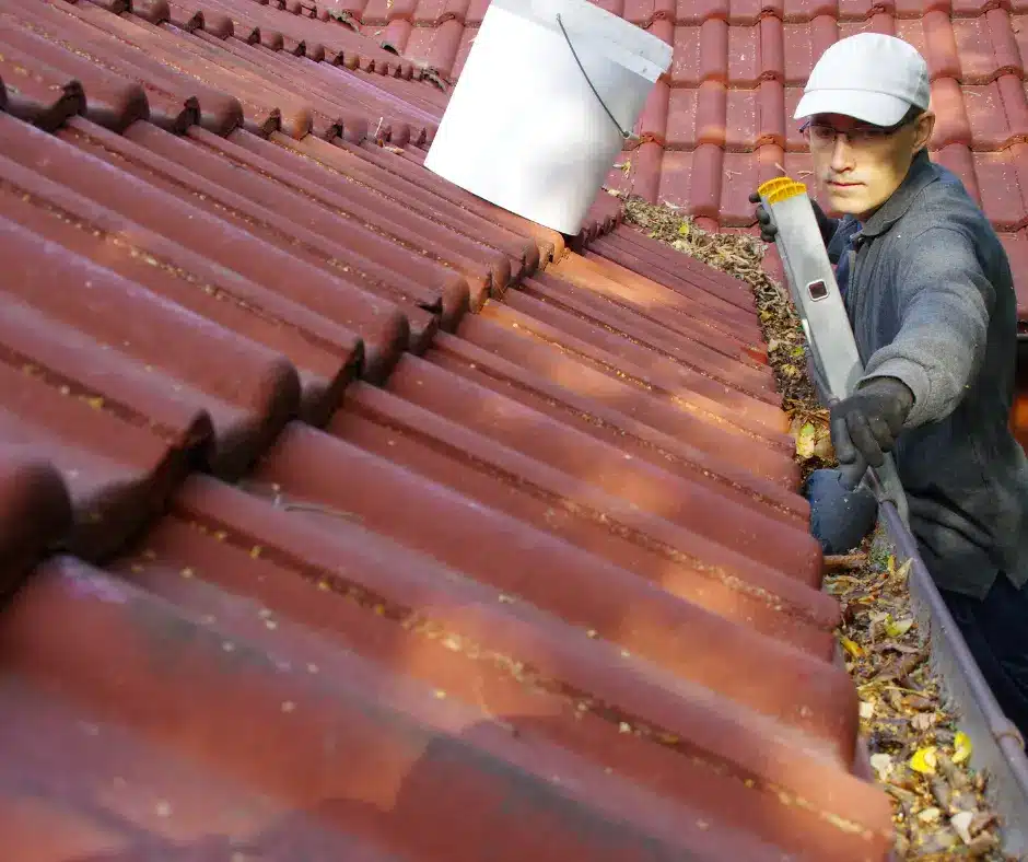 a man cleaning the gutters of a roof