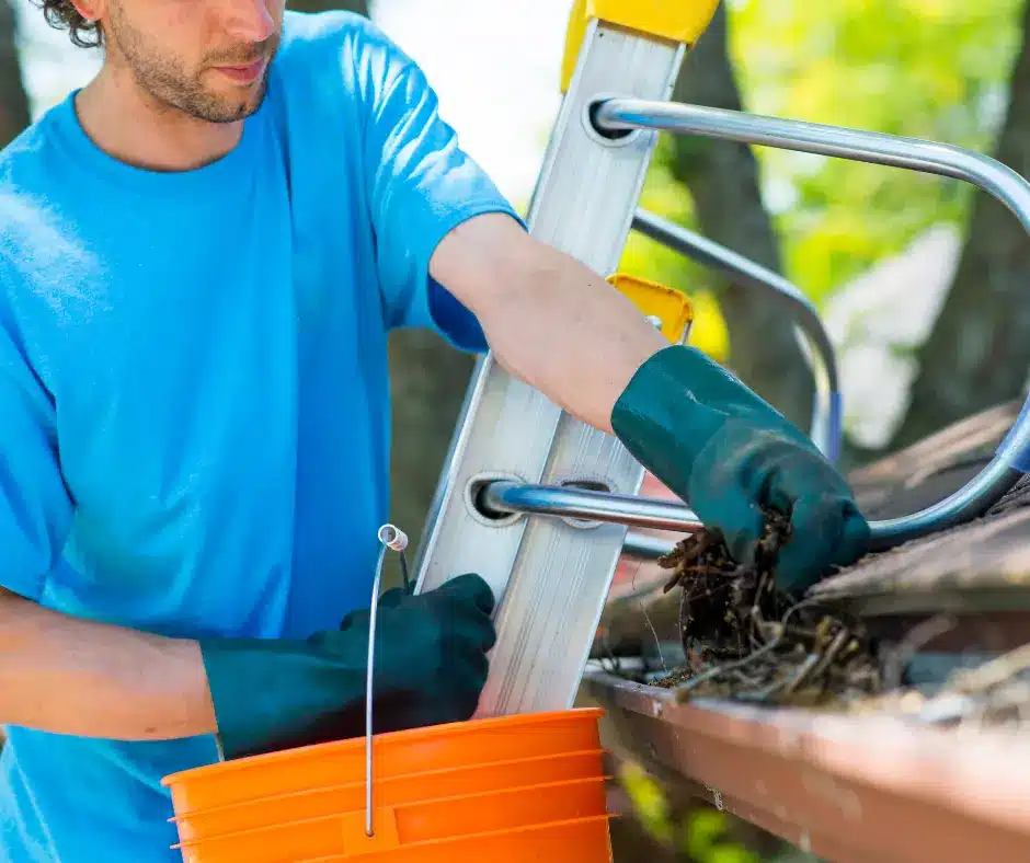 a man holding a bucket in a ladder, cleaning a newly replaced eavestrough