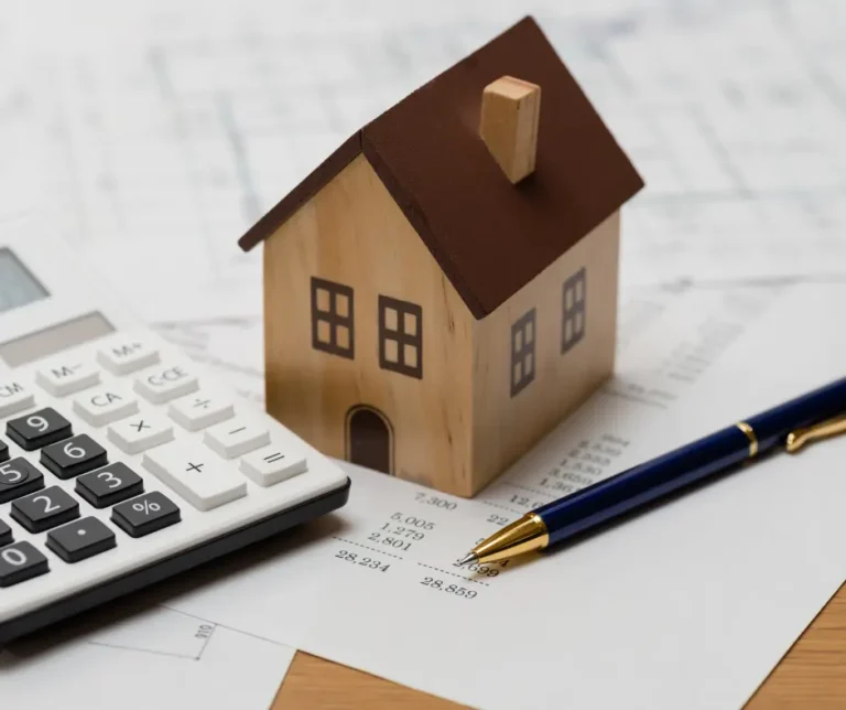 a small wooden house next to a calculator and pen