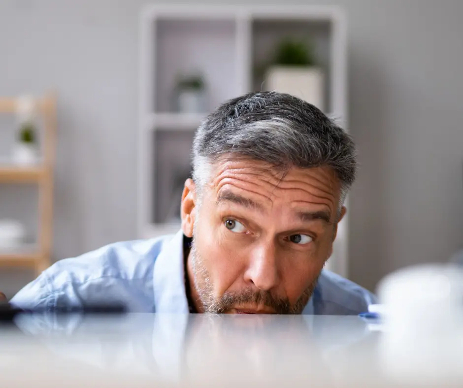 a man hiding behind a table