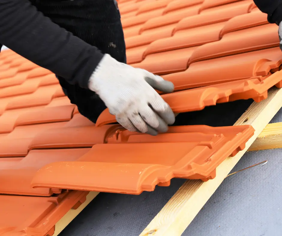 a person wearing gloves and holding a roof tile