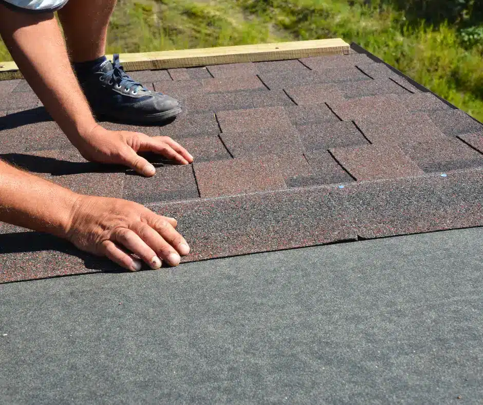 a person's hands on a roof installing IKO cambridge shingles