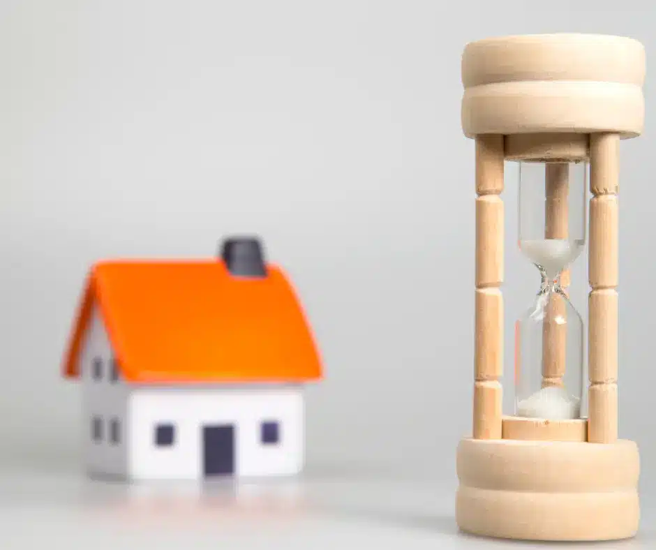 a wooden hourglass next to a small house