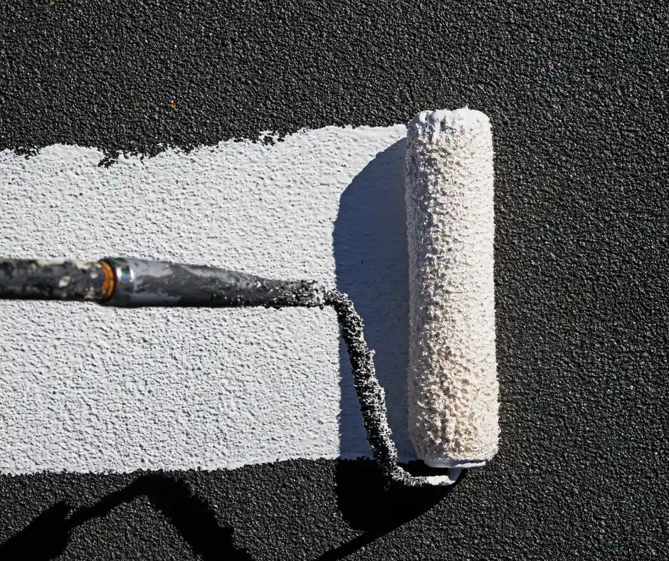 a roller painting a white line on a black surface