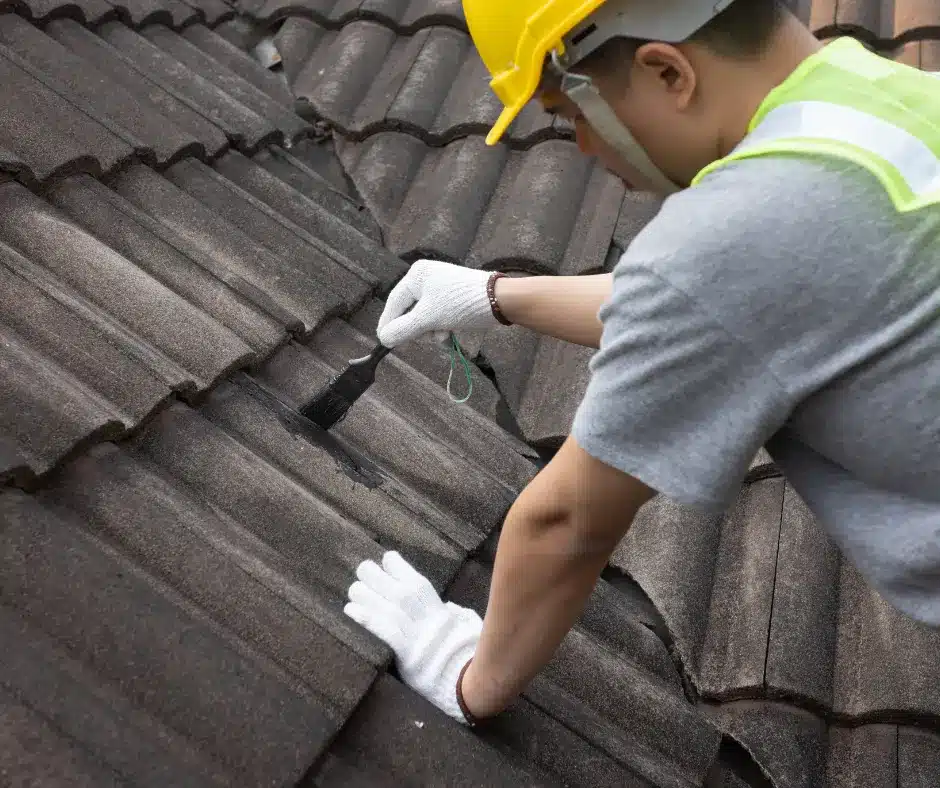 a man wearing a hard hat and gloves fixing a roof