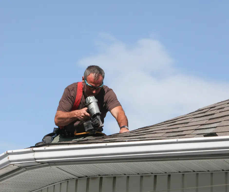 a roofer using a drill on a roof