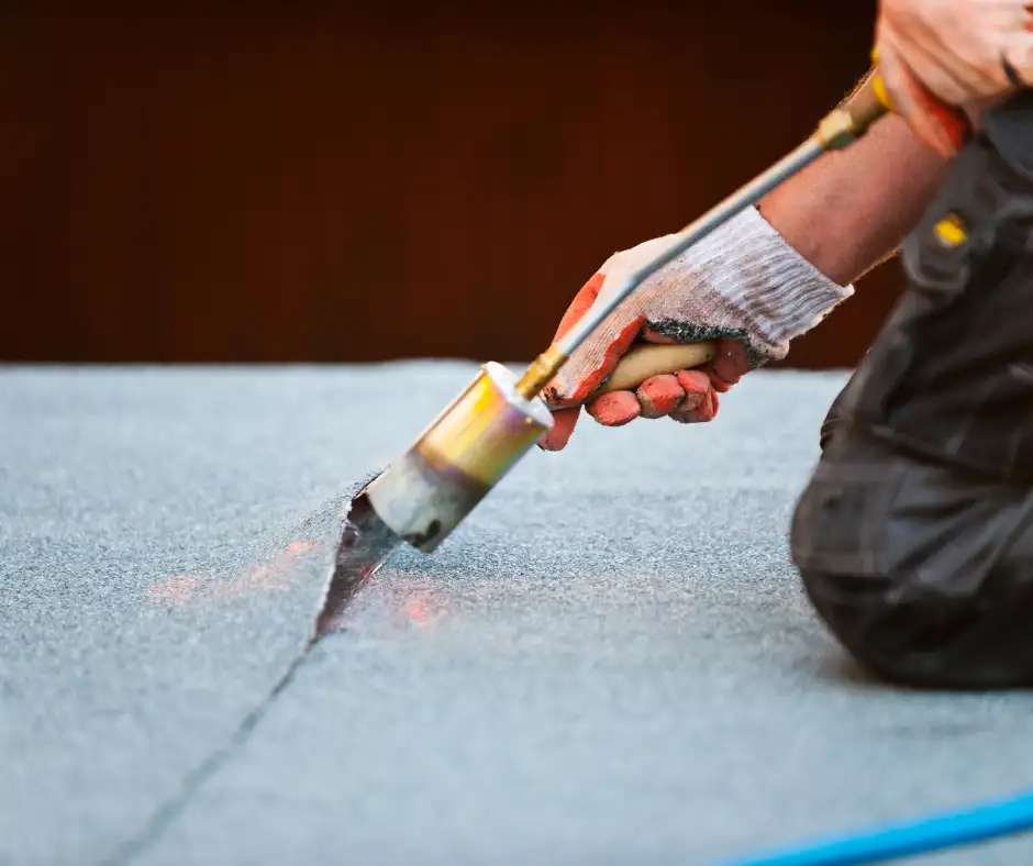 a person using a blowtorch to seal the roof felt