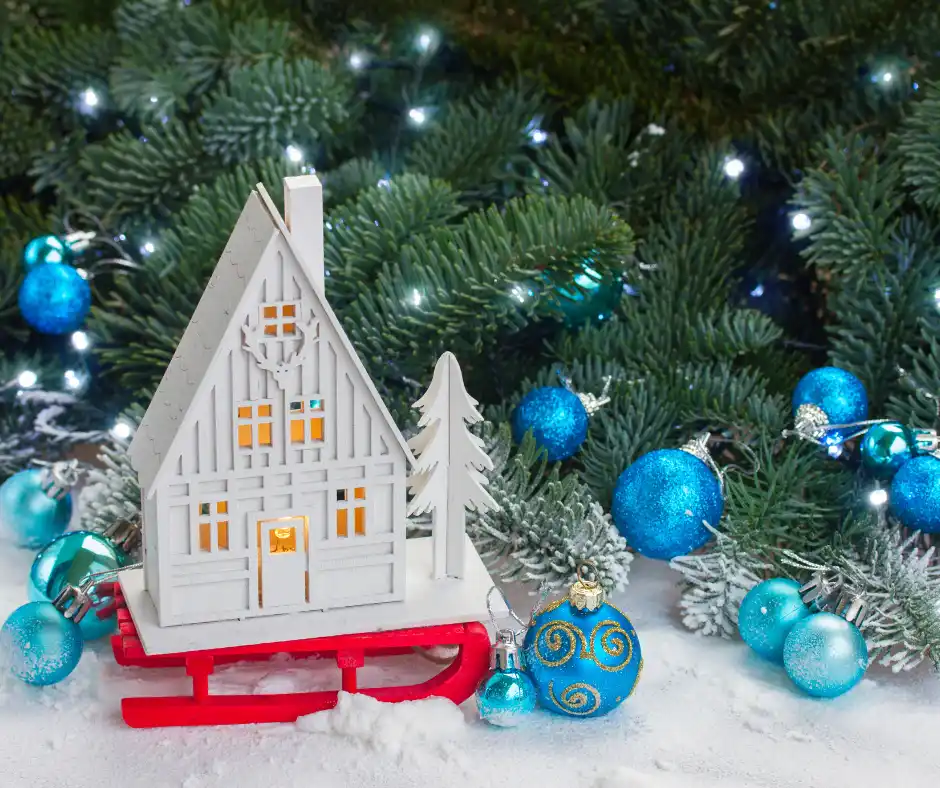 a small white house on a sled with blue and white ornaments