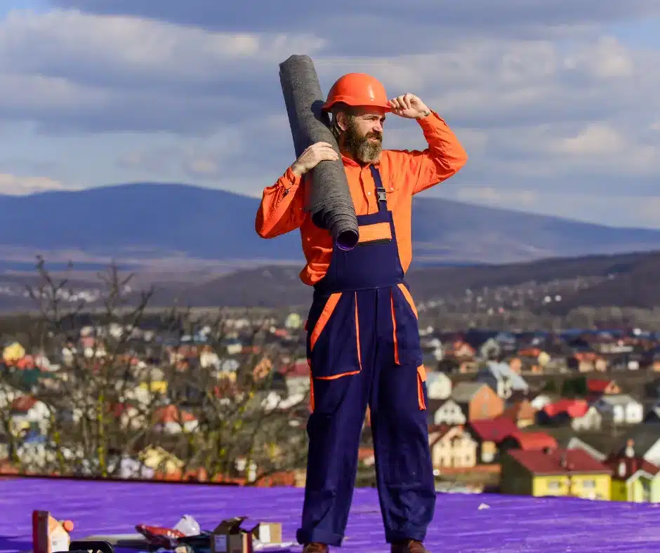 a man in overalls holding a roll of roofing felt