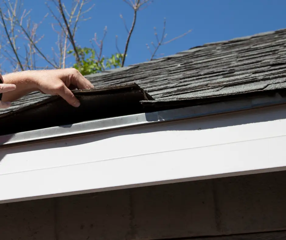 a person's hand on a roof shingles, one of the parts of a roof