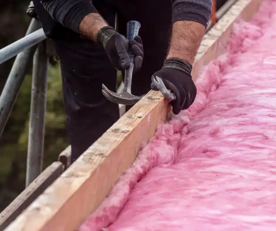 a person holding a hammer and nail on a wood beam